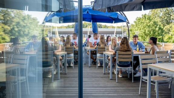 Eine Gruppe trifft sich auf der Sonnenterrasse zu einem Getränk