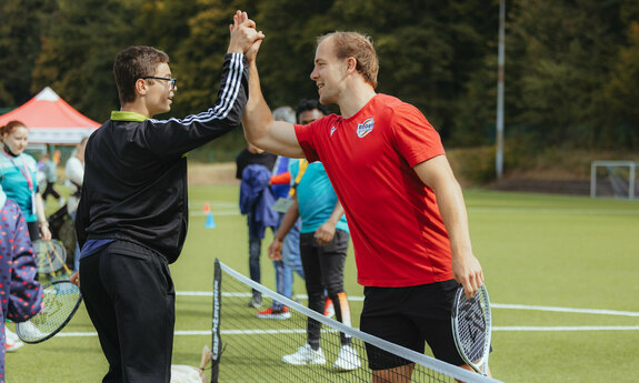 Zwei Athleten klatschen nach dem Tennisspiel ein