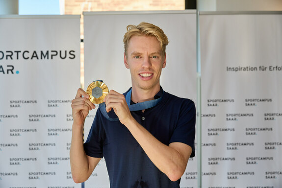 Triathlet Tim Hellwig zeigt seine olympische Medaille